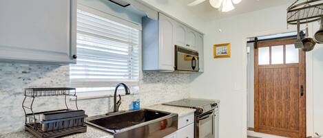 A kitchen with a granite countertop, stainless steel sink, and a ceiling fan.