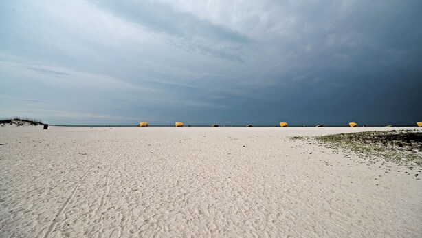 Una amplia playa de arena con dunas y cielo despejado.