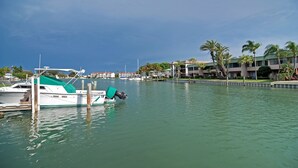 Un puerto deportivo con barcos amarrados, cielo despejado y edificios al fondo.
