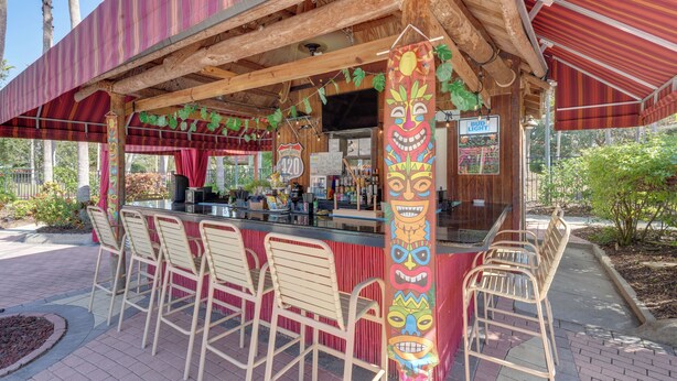 Eine Tiki-Bar im Freien mit Theke, Barhocker und Holzkonstruktion.