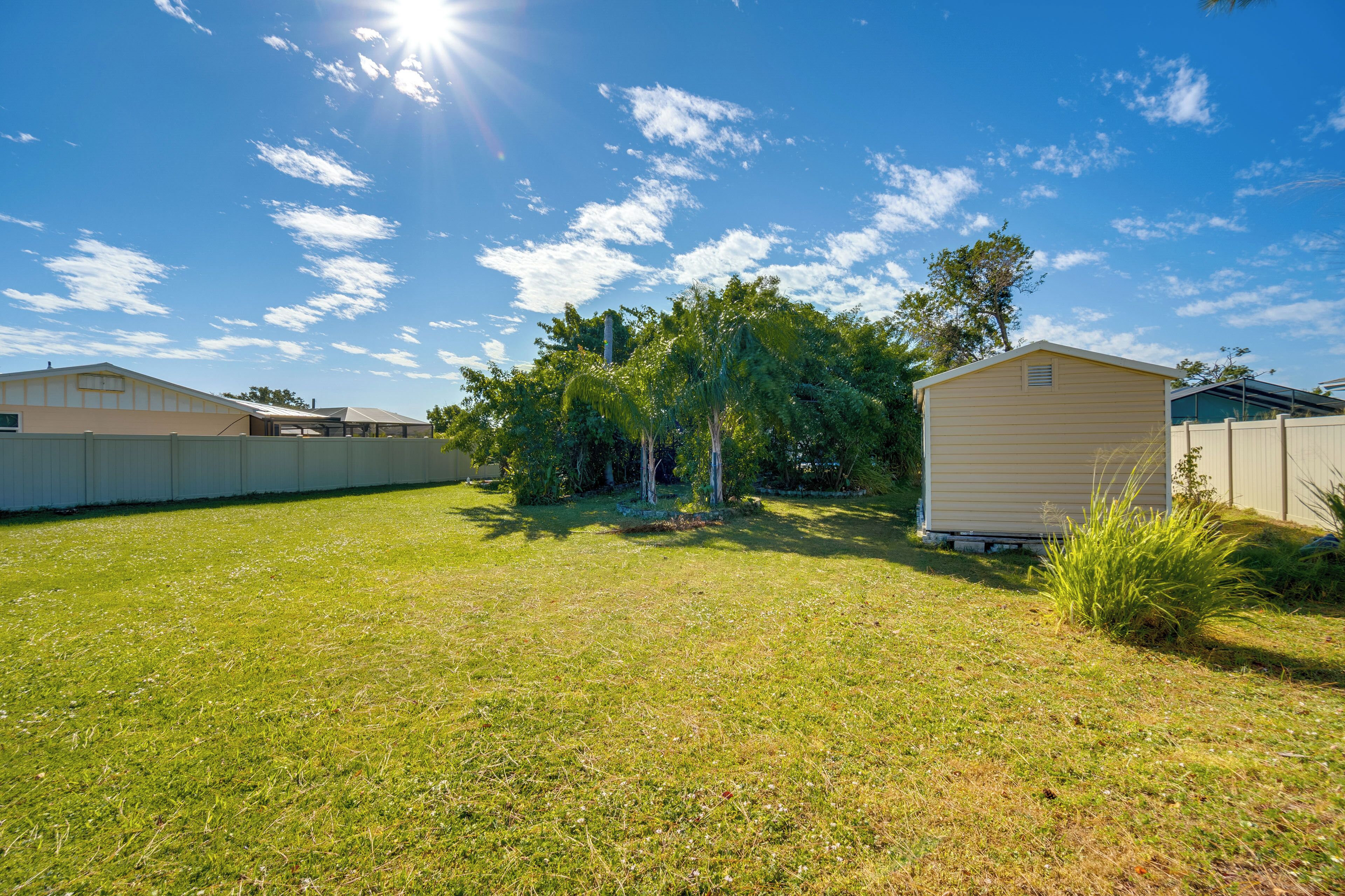A residential backyard with a small shed, a lawn, and a fence.