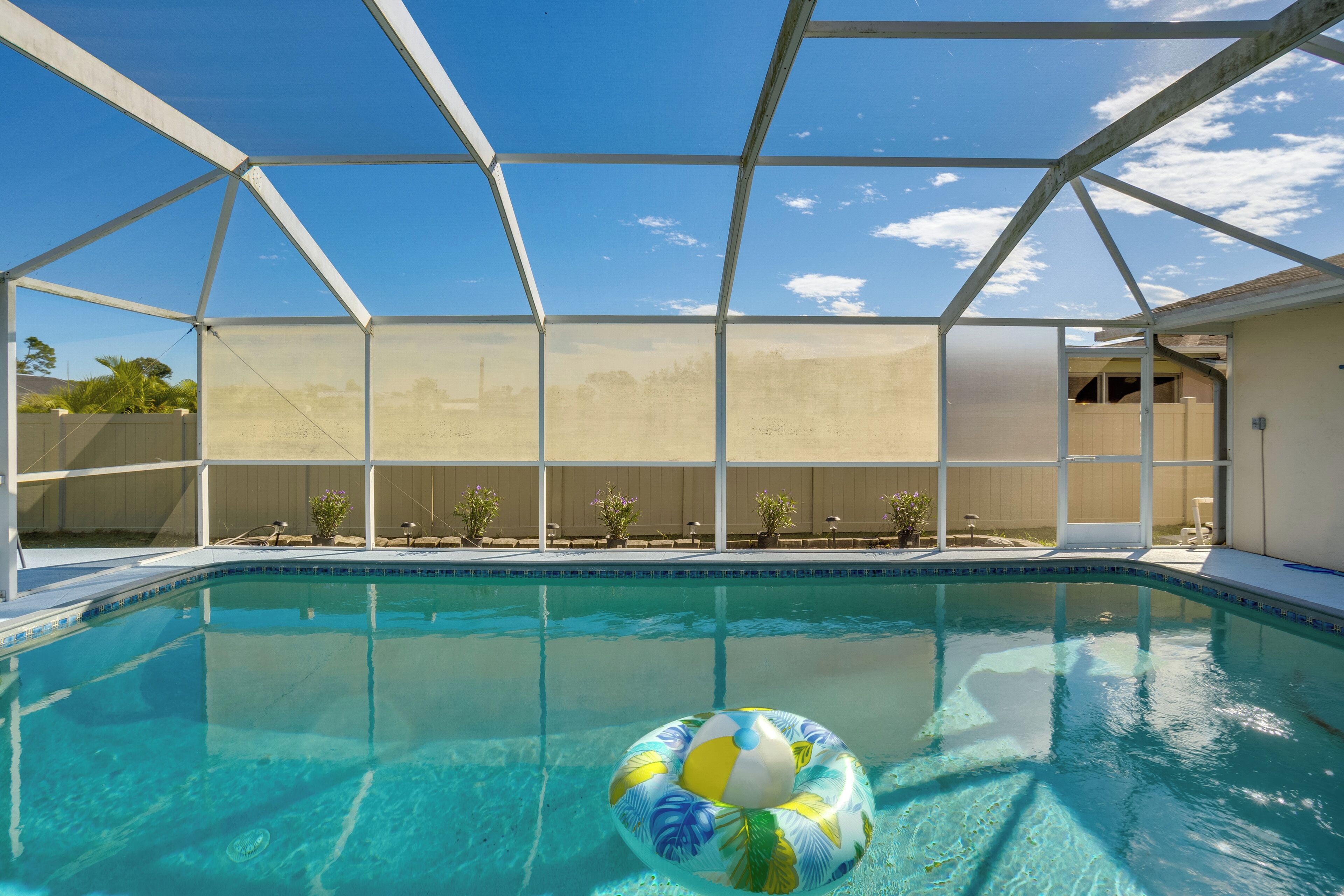 An indoor swimming pool with a clear blue sky visible through a transparent roof structure.