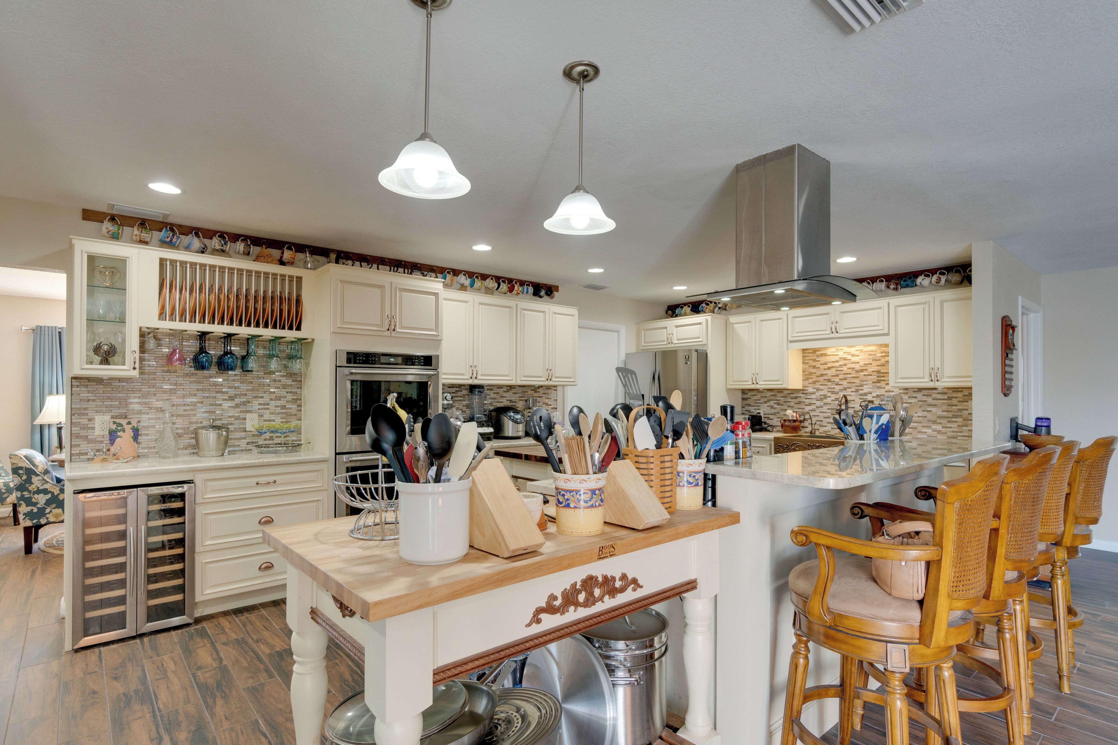 A modern kitchen with white cabinetry, a central island with bar stools, and various kitchen appliances.