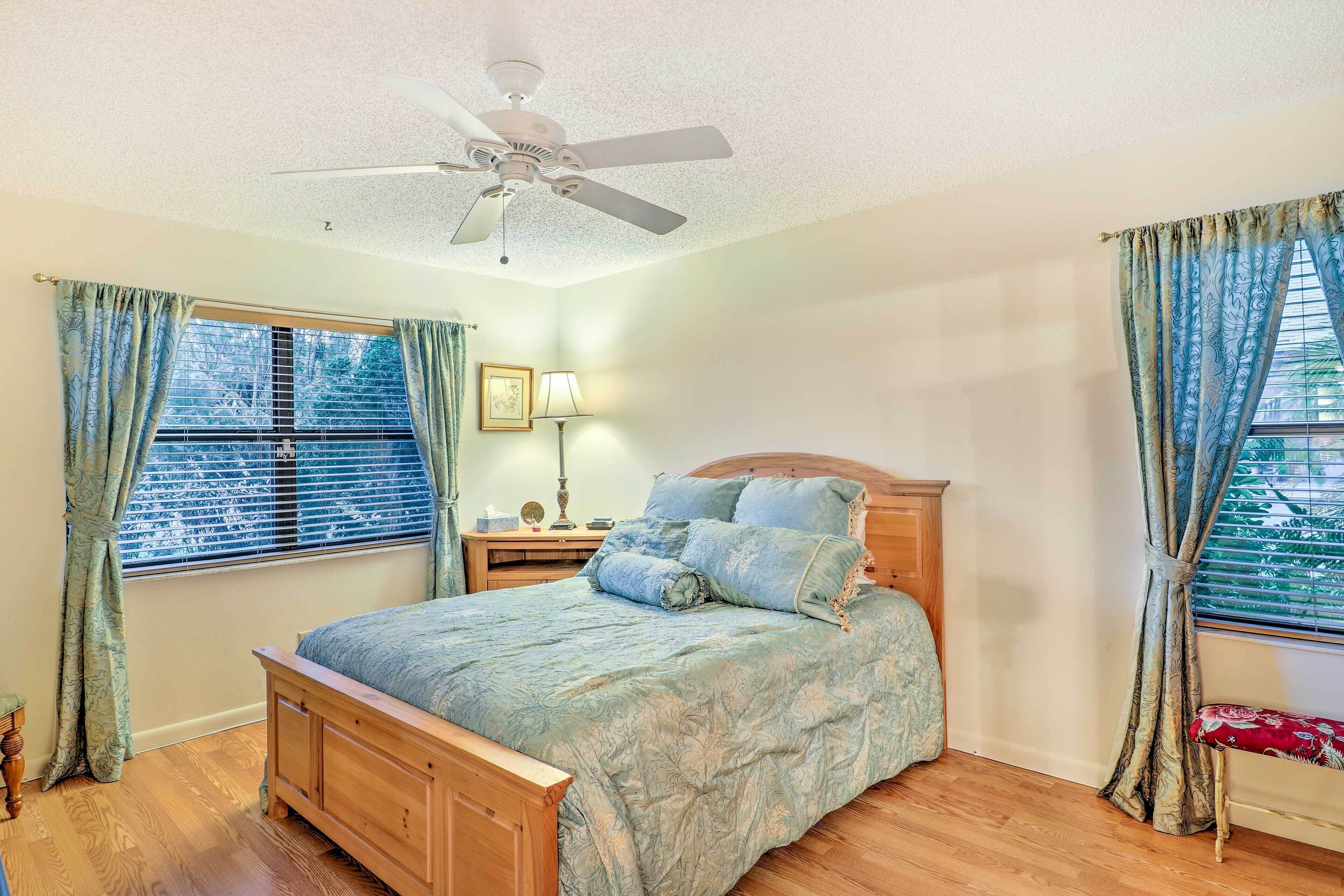 A bedroom with a wooden bed, a ceiling fan, and a window with blinds.