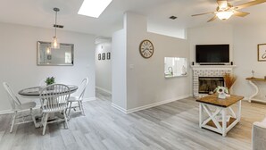 Ein modernes Wohnzimmer mit Kamin, Essbereich mit rundem Tisch und Stühlen sowie Deckenventilator.