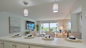 Una cucina moderna con isola centrale, illuminazione a sospensione e vista sull'area soggiorno.