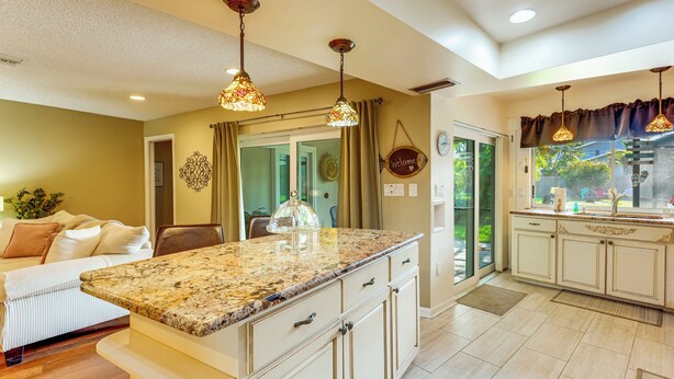A kitchen with granite countertops, white cabinetry, and pendant lighting.