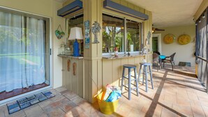 A kitchen with a bar area, a sliding glass door, and a small outdoor seating area with a table and chairs.