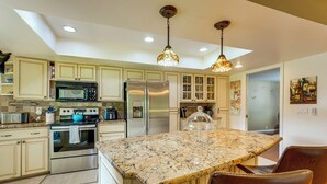 A kitchen with granite countertops, stainless steel appliances, and pendant lighting.