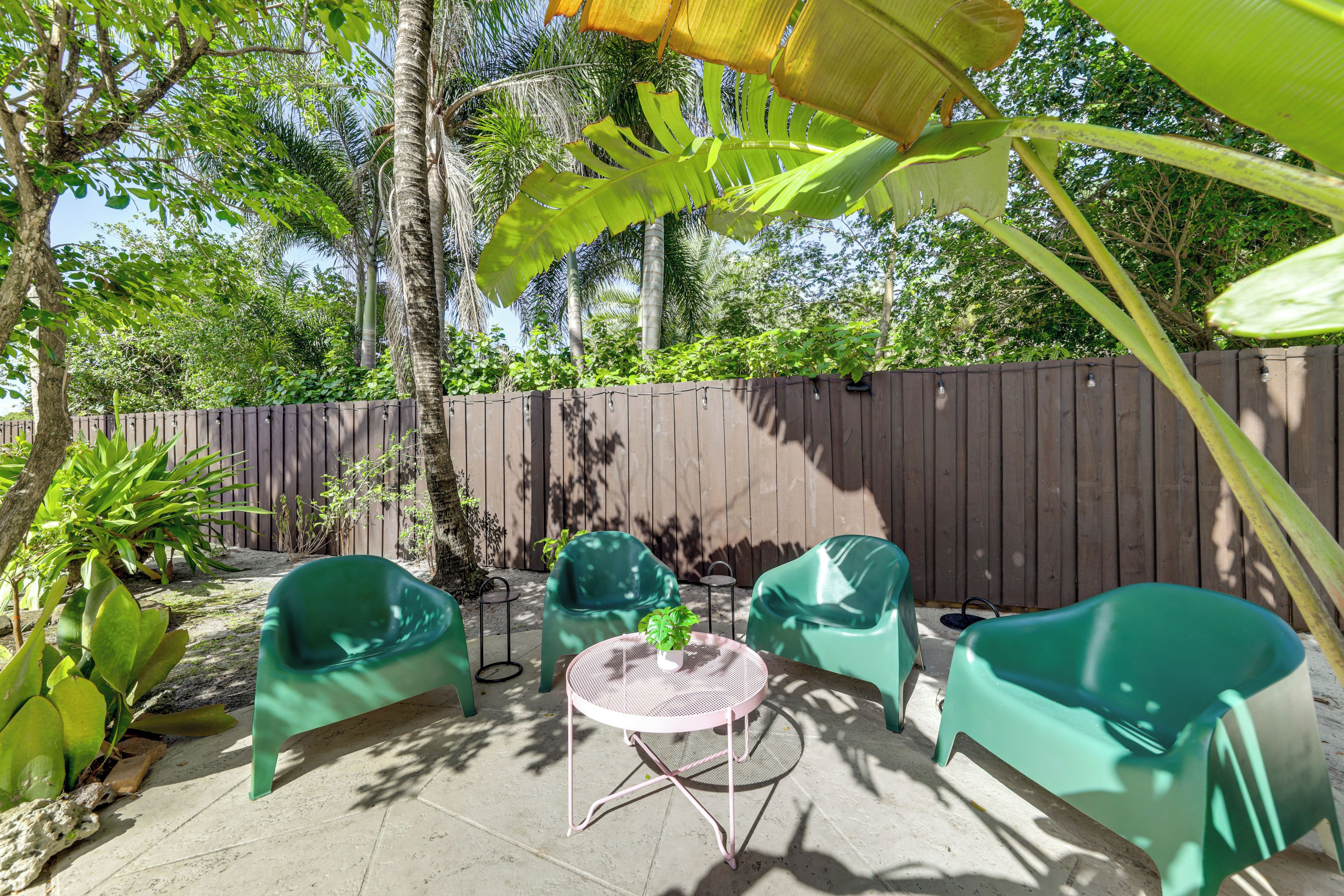 An outdoor patio with two green chairs, a small round table, and a potted plant.