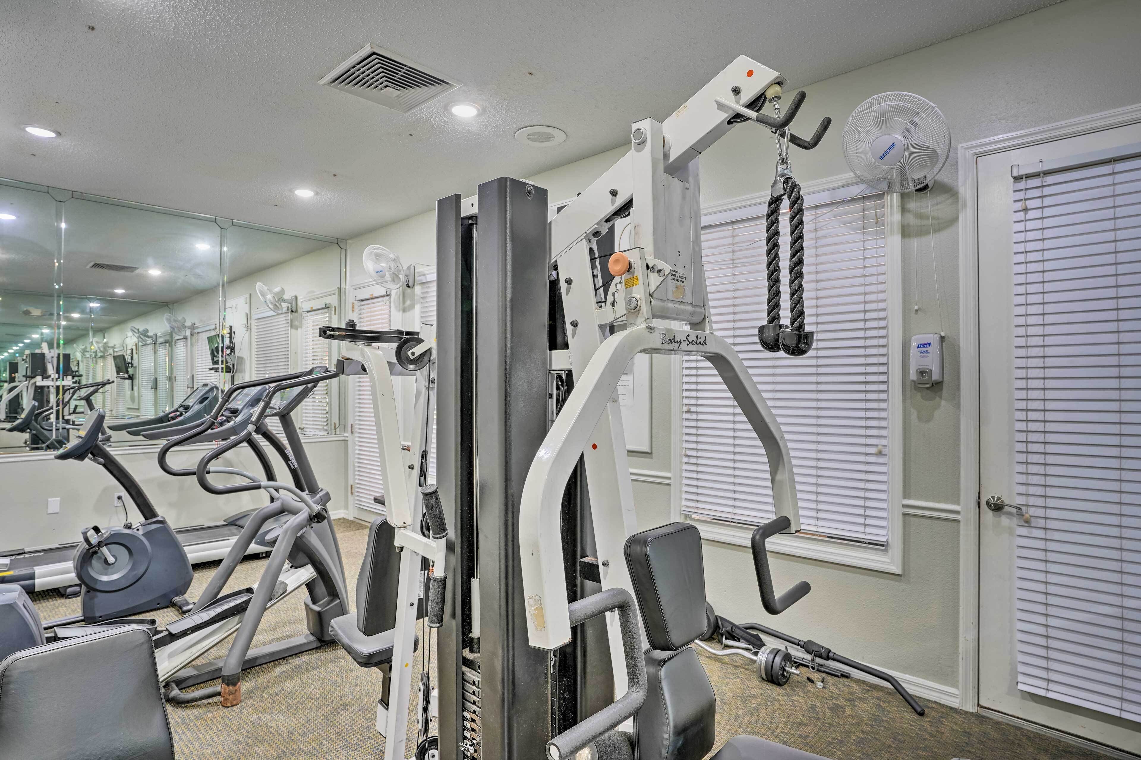 Une salle de sport équipée de machines de cardio, d’appareils de musculation et dotée d’un mur entièrement recouvert de miroirs.