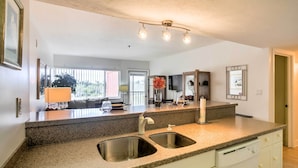 A kitchen with granite countertops, stainless steel sinks, and a dishwasher. There is a ceiling light fixture above the counter. - Resort-style Condo w/ Pool: 19 Miles to Fort Myers (Punta Gorda)