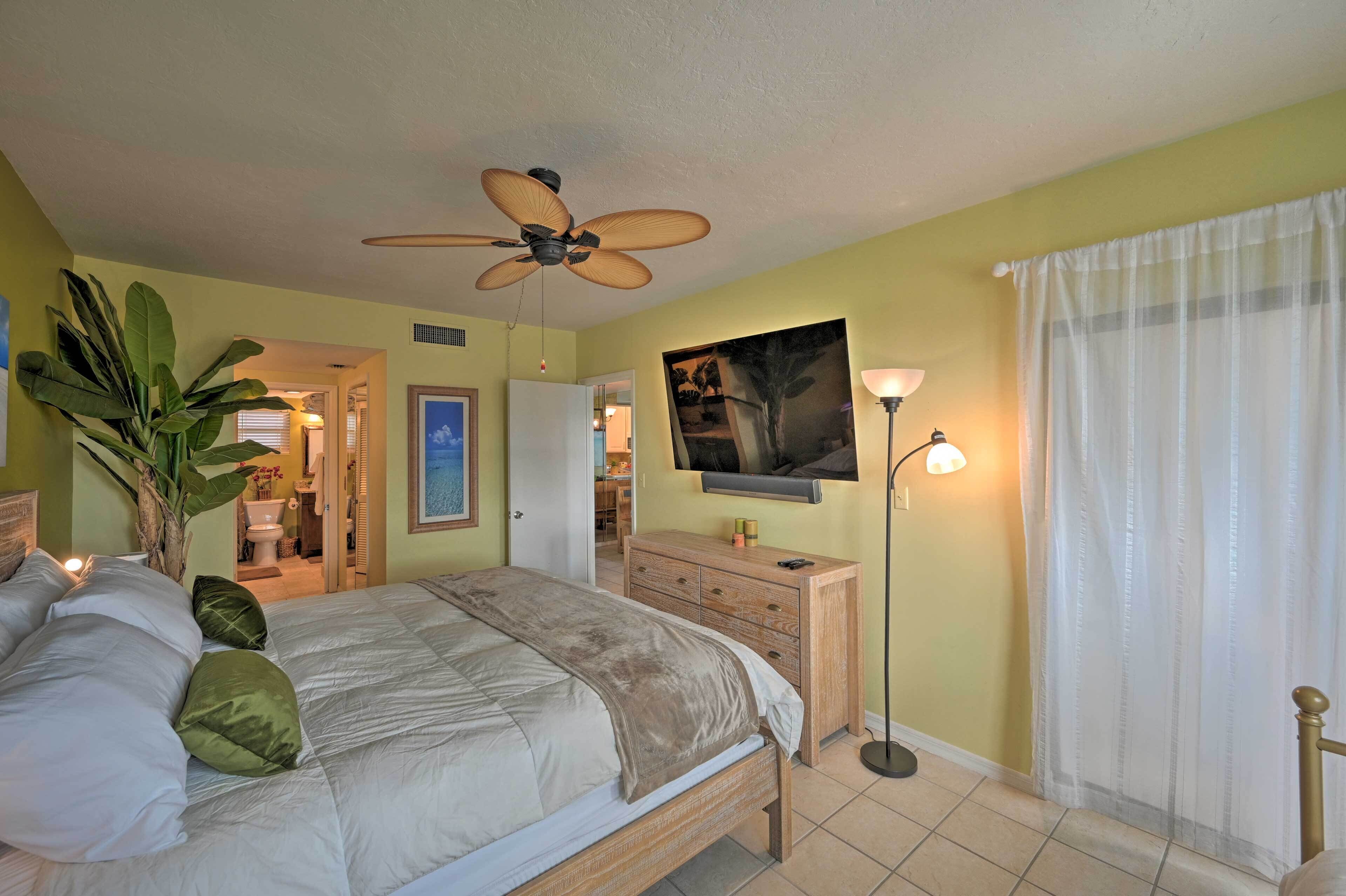 A bedroom with a bed, a ceiling fan, a television, and a nightstand.