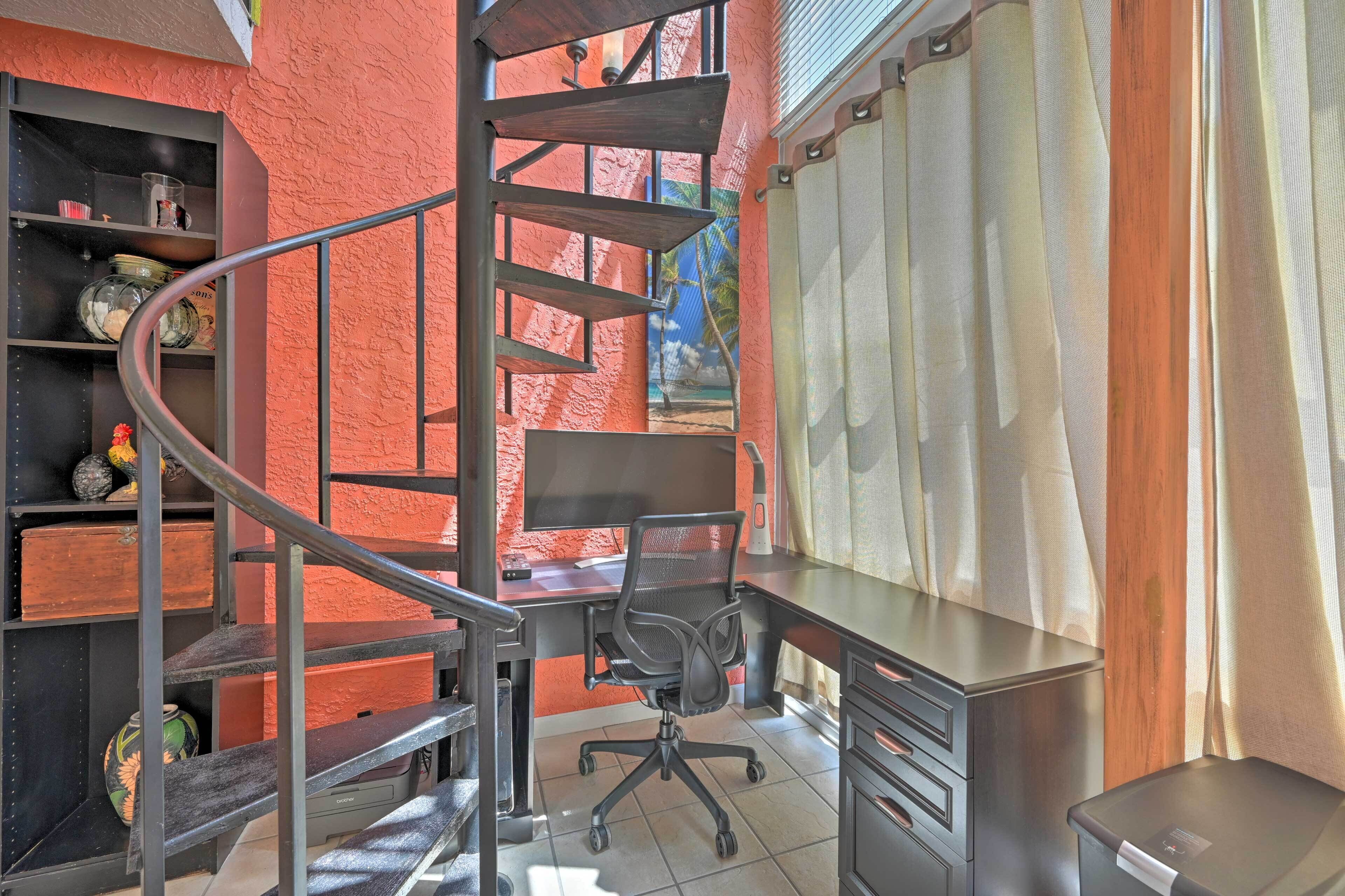 Une pièce dotée d’un escalier en colimaçon, d’un bureau avec une chaise et d’étagères remplies de divers objets.