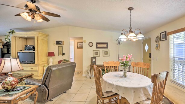 A dining area with a round table, chairs, a ceiling fan, and a television in the background. - Quincy Home w/ Deck & Outdoor Patio Furniture (Quincy)