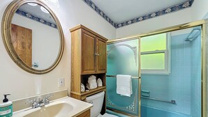 A bathroom with a wooden cabinet, a sink, a toilet, and a glass-enclosed shower. - Dock & Kayaks: Riverfront Dunnellon Home! (Dunnellon)