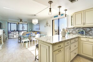 Una cocina amplia con una isla grande, comedor de vidrio transparente y vistas al exterior.