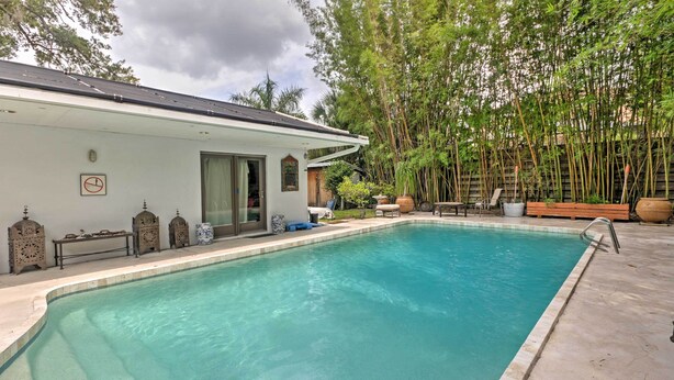 A swimming pool with a white building, outdoor seating, and bamboo plants. - Sarasota House w/ Backyard Oasis: 6 Mi to Beach! (Sarasota)