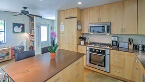 A modern kitchen with wooden cabinets, a stainless steel oven, a microwave, and a dining area with a wooden table and chairs. - Sarasota House w/ Backyard Oasis: 6 Mi to Beach! (Sarasota)