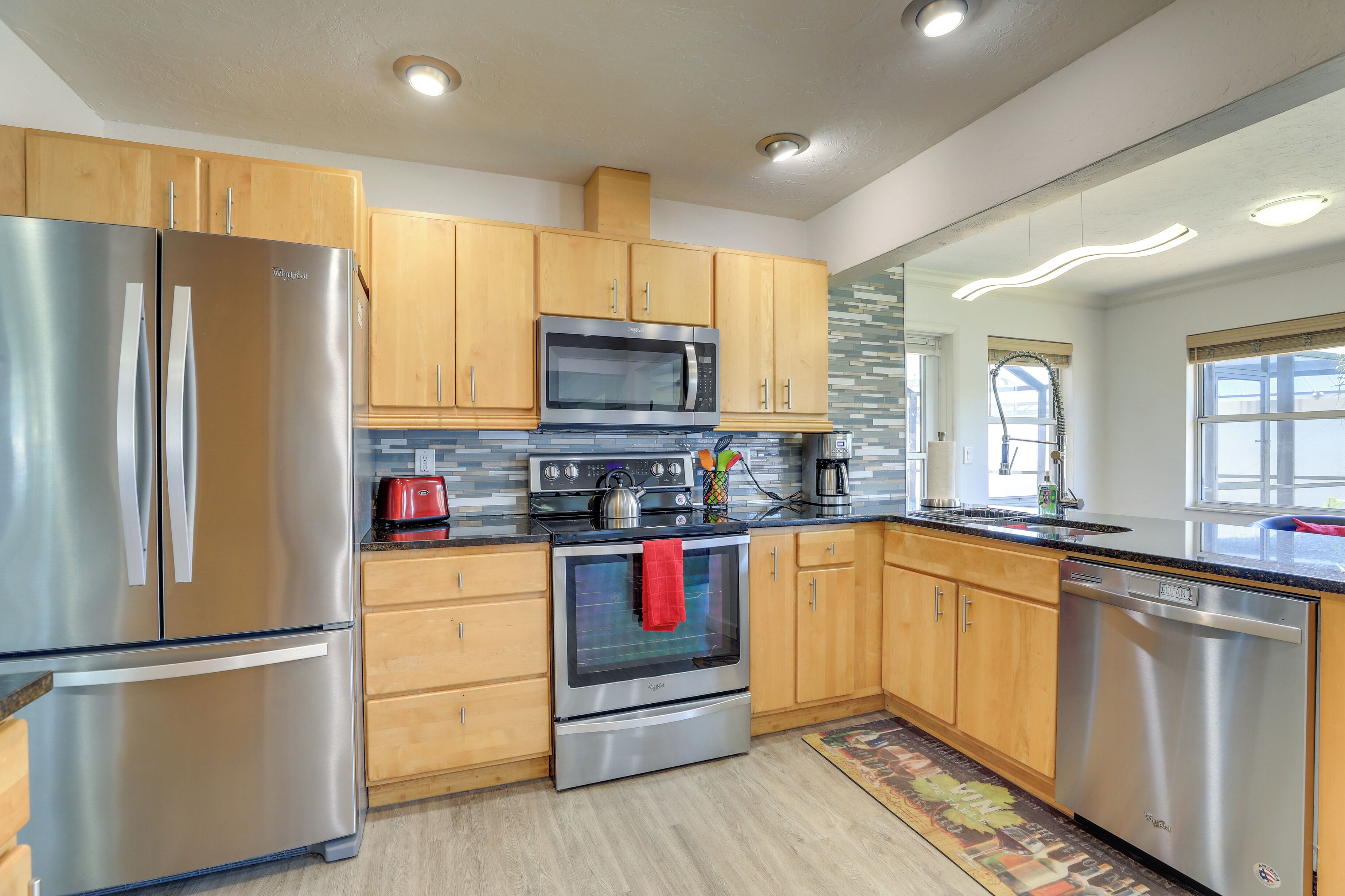 A modern kitchen with stainless steel appliances, wooden cabinets, and a tiled backsplash.