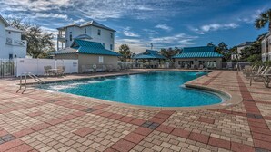 Une piscine dotée d’une terrasse carrelée, de chaises longues et d’un bâtiment surmonté d’un toit bleu.