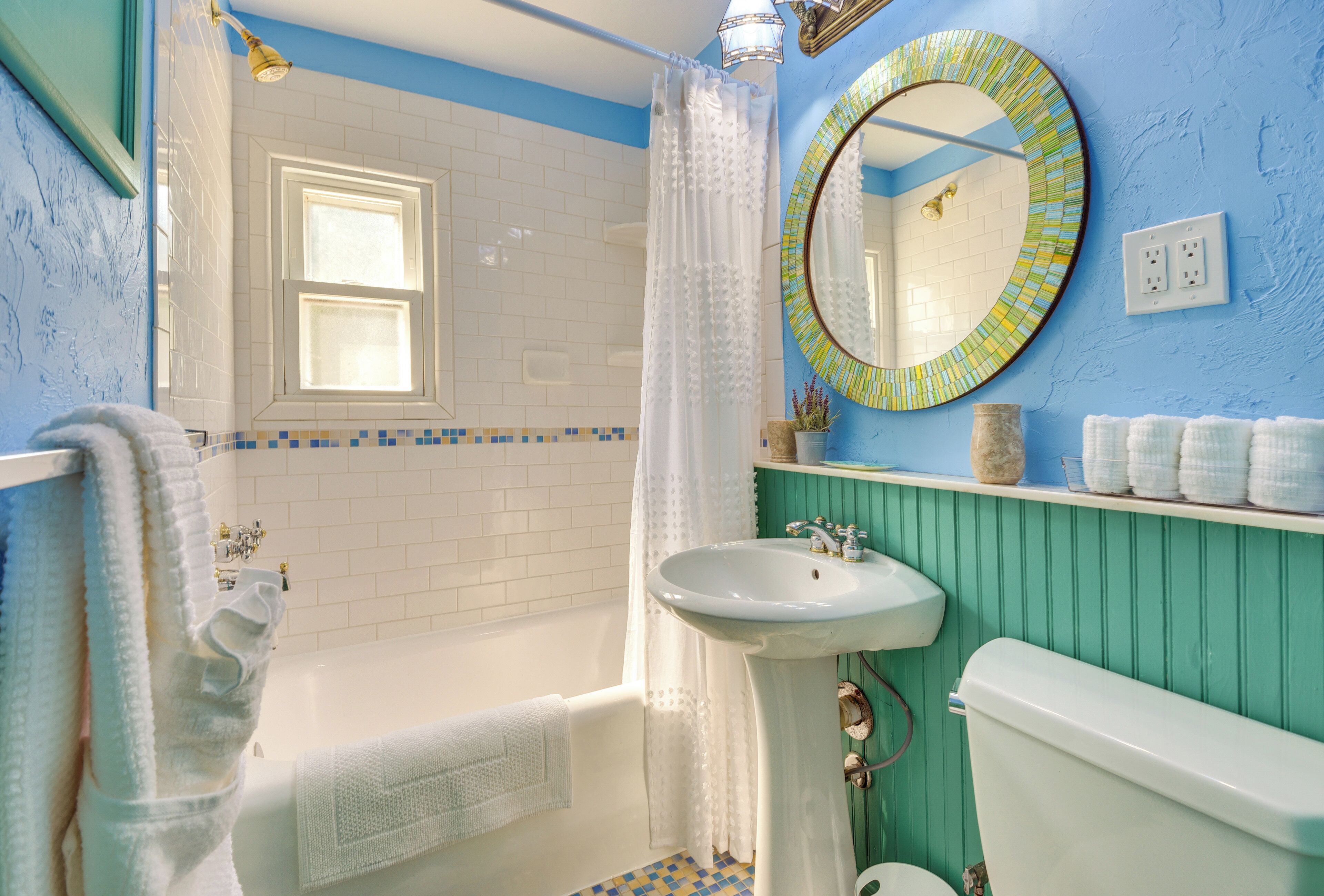 A bathroom with a bathtub, a sink, a toilet, and a window.