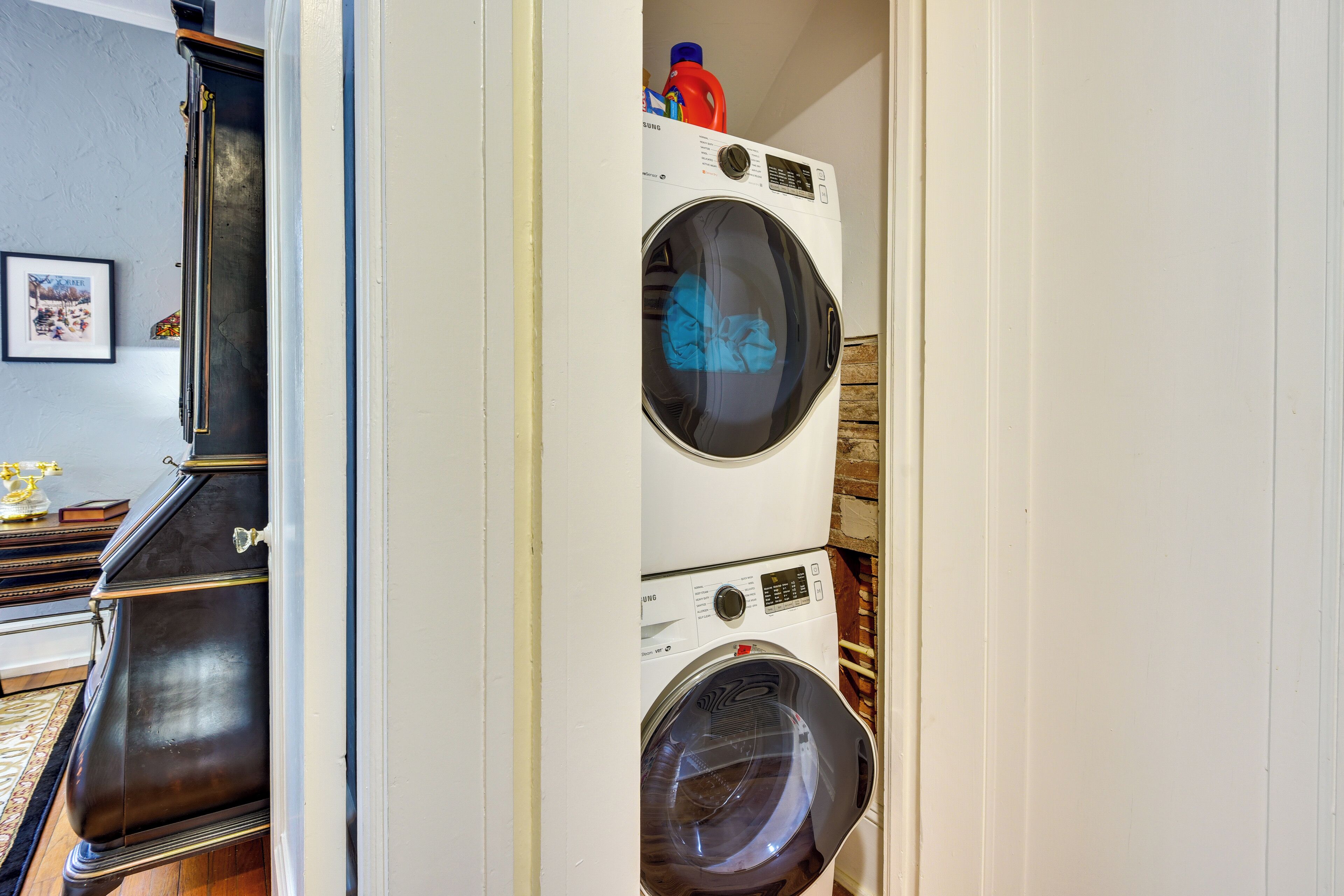 A laundry room with stacked washing machines and a wooden cabinet.