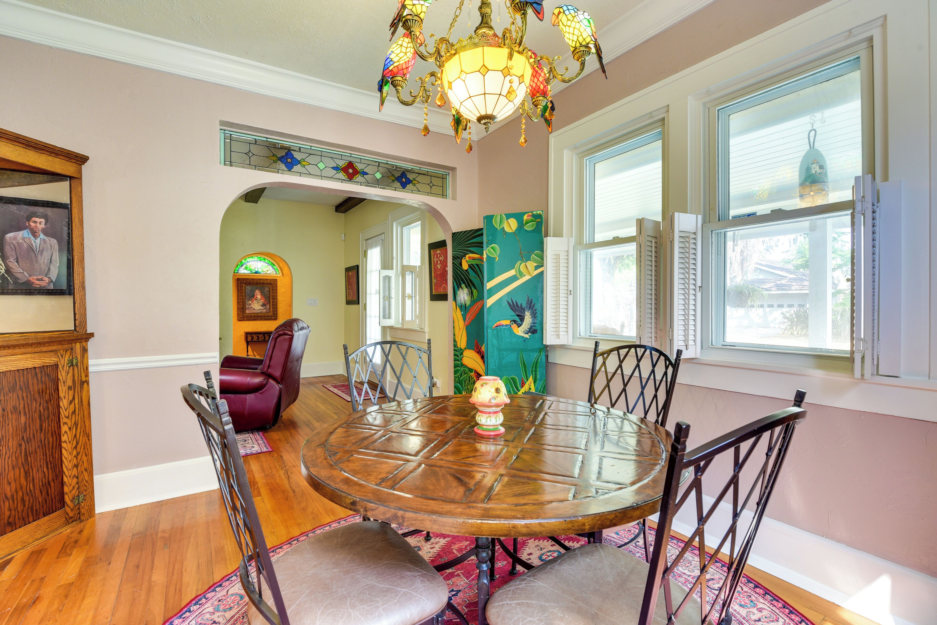 A dining area with a round wooden table, four chairs, and a chandelier.