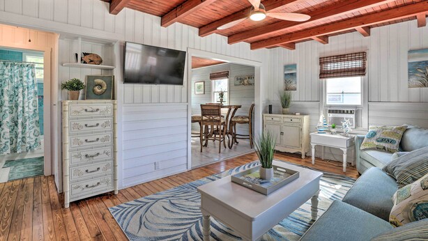 A spacious living room with a wooden ceiling, a flat-screen TV, a dining area with a table and chairs, and a cozy seating area with a sofa and cushions. - Siesta Key Village Home < Half Mi to Beach! (Siesta Key)