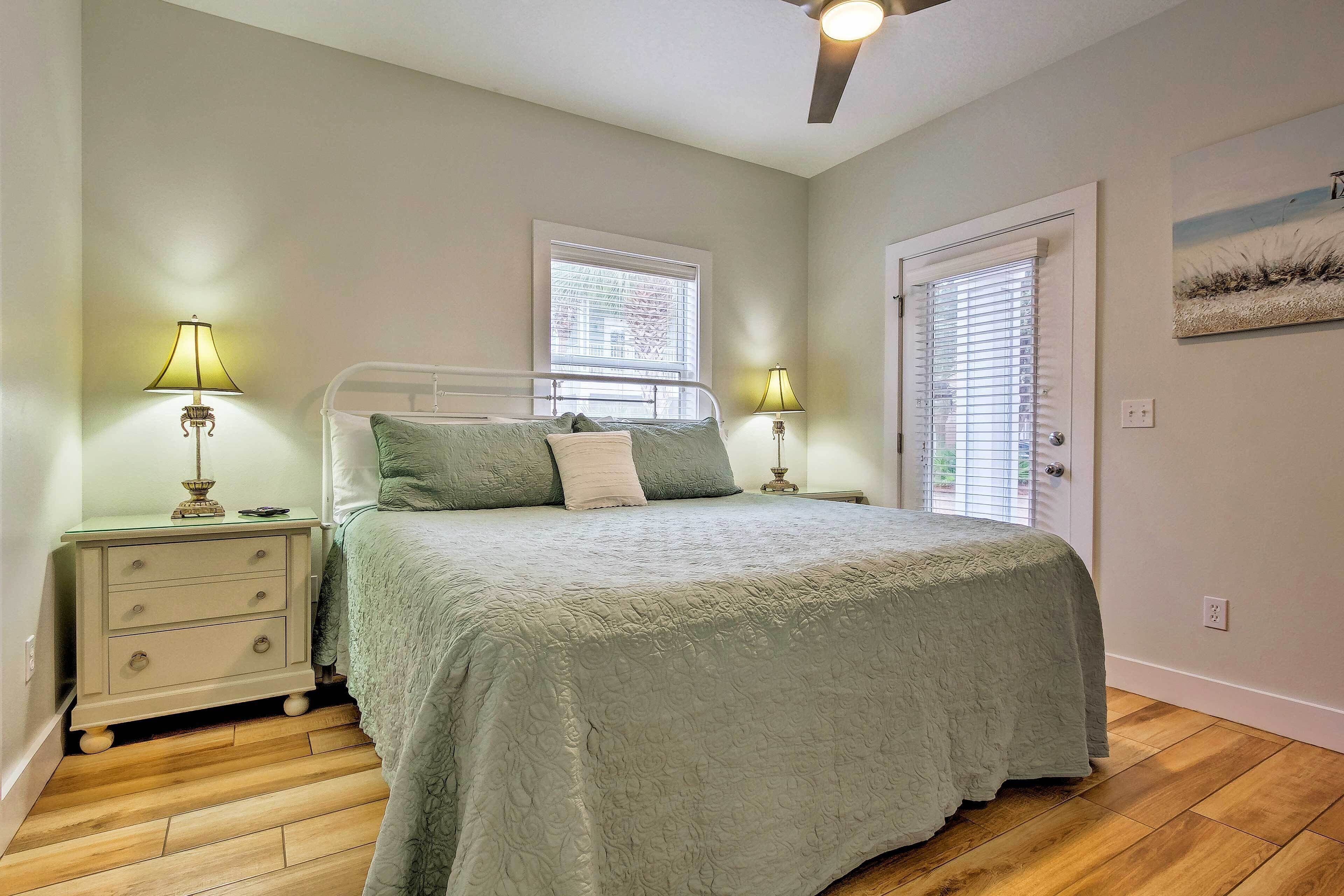 A bedroom with a bed, two bedside lamps, a nightstand, a window, and a door.