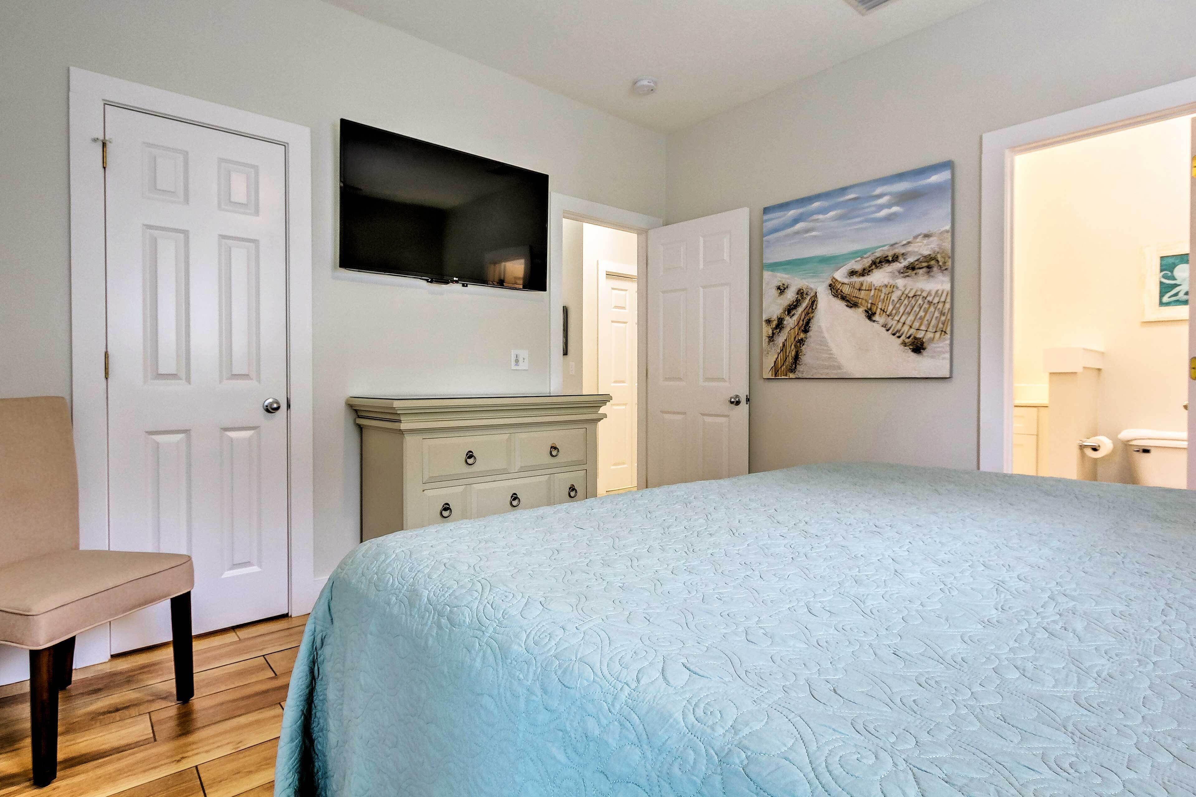 A bedroom with a bed, dresser, and a painting of a beach scene.