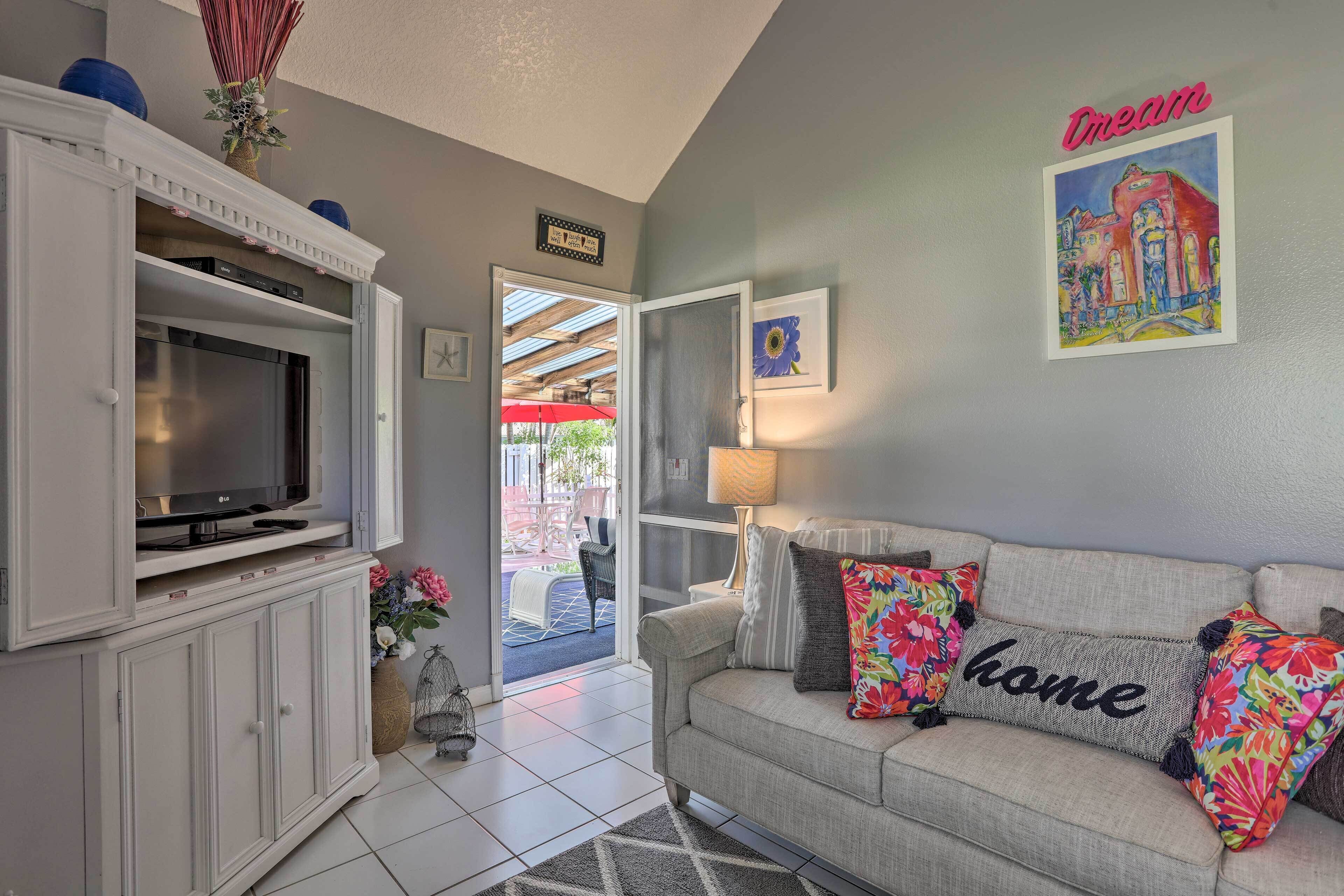 A living room with a sofa, television, and decorative pillows.