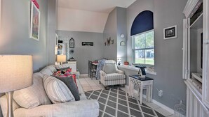 A living room with a sofa, armchair, and a patterned rug. There is a dining area with a table and chairs. - Stuart Apartment w/ Patio Near St Lucie River! (Stuart)