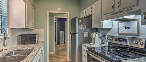 A kitchen with granite countertops, stainless steel appliances, and white cabinetry.