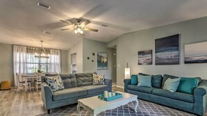 A living room with two sofas, a coffee table, and a dining area with a table and chairs. - Stellar Fort Walton Retreat ~ 2 Mi to Beach! (Fort Walton Beach)