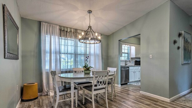 A dining area with a round table, white chairs, and a chandelier. - Stellar Fort Walton Retreat ~ 2 Mi to Beach! (Fort Walton Beach)