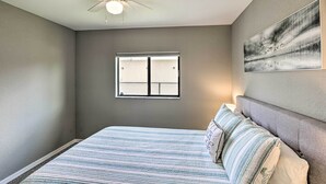 A bedroom with a bed, a ceiling fan, a window, and a wall-mounted artwork. - Stunning Cape Coral Home w/ Open Floor Plan! (Cape Coral)