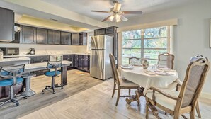 A modern kitchen with dark cabinets, a stainless steel refrigerator, and a dining area with a table and chairs. - Sunny Crystal River Home w/ Screened-in Porch (Crystal River)