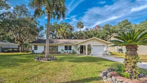 A single-story house with a front yard, a garage, and a bicycle parked outside. - Sunny Crystal River Home w/ Screened-in Porch (Crystal River)