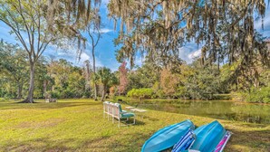 A grassy area with a pond, chairs, and kayaks. - Sunny Crystal River Home w/ Screened-in Porch (Crystal River)