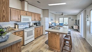 Eine moderne Küche mit Holzausstattung, einer zentralen Kochinsel mit Sitzgelegenheiten, einer Mikrowelle, einem Herd und einem Kühlschrank.