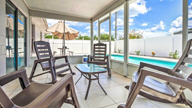 Um alpendre coberto com vista para a piscina, mobiliário de exterior e ventoinha de teto.