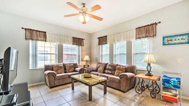 A living room with a sofa set, a coffee table, a TV, and a lamp. - Kissimmee Resort Townhome w/ Pool, 7 Mi to Disney! (Kissimmee)