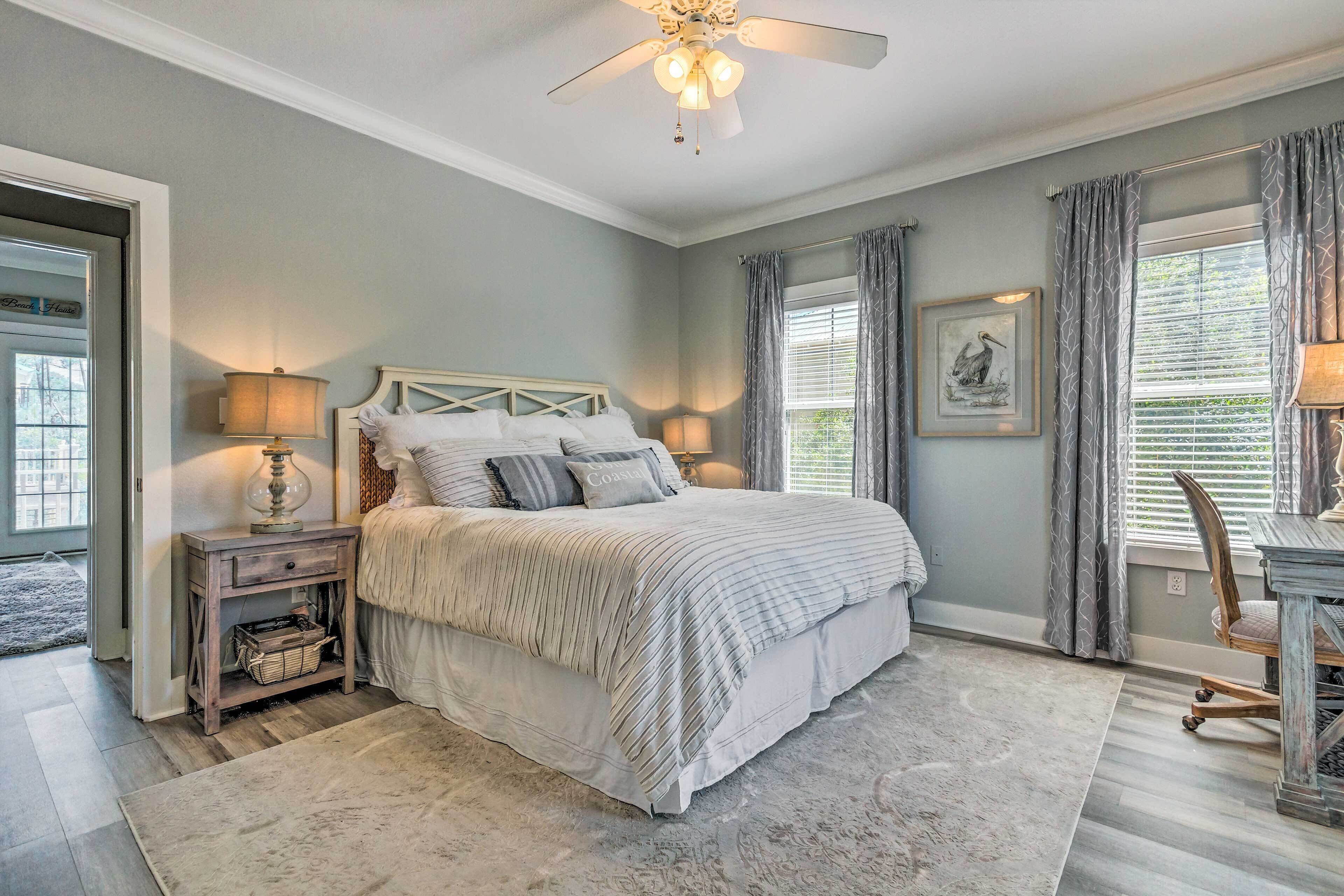A bedroom with a bed, bedside tables, a ceiling fan, and a window with curtains.