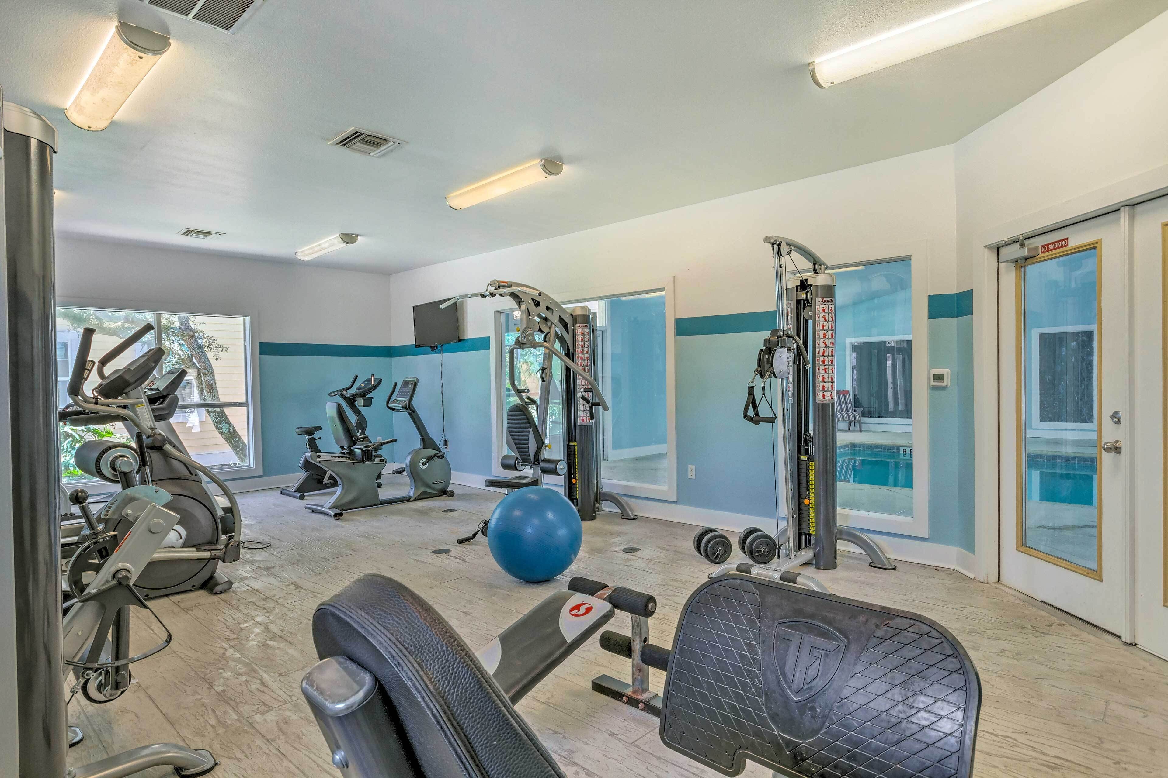 A gym with various exercise equipment, a blue exercise ball, and a bench.
