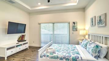 A bedroom with a bed, a TV, a nightstand, and a window with blinds.