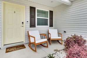 A porch with two rocking chairs, a door, and a window with shutters. - The Villages Home w/ Golf Cart & Community Pools! (Wildwood)