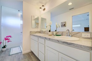 Un bagno moderno con due lavabi, un ampio specchio e un'orchidea in vaso.
