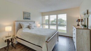 A bedroom with a bed, a dresser, a nightstand, and a window with blinds.