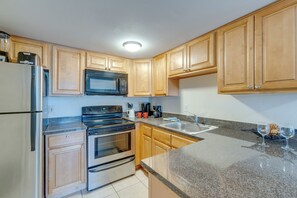 A modern kitchen with wooden cabinets, stainless steel appliances, granite countertops, and a built-in microwave.